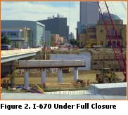 Picture shows a bridge crossing I-670 that is being expanded.  Traffic flows on half of the bridge, with only the base constructed on the expanded section.  The roadway surface has been removed from I-670 below the bridge with construction equipment having full access to the facility.