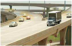  A photo shows a highway overpass with traffic on the right and traffic from a ramp on the left merging into the flow.
