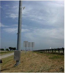 A photograph shows equipment mounted on a pole at the side of a road.