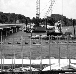 The cover photo shows the side of the Lake Springfield Bridge under construction. In the foreground, metal framing for concrete is visible. In the midground, several construction cranes that have been placed on barges next to the bridge are visible. Traffic can be seen crossing the bridge.