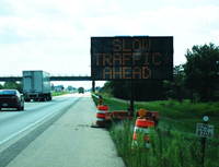 Changeable message sign warns approaching vehicles of slow traffic ahead.