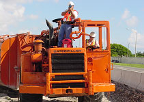 photo of workers on a road maintenance machine aiming a radar gun