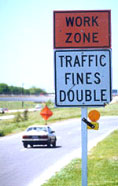 photo of signs next to roadway stating "work zone, traffic fines double"